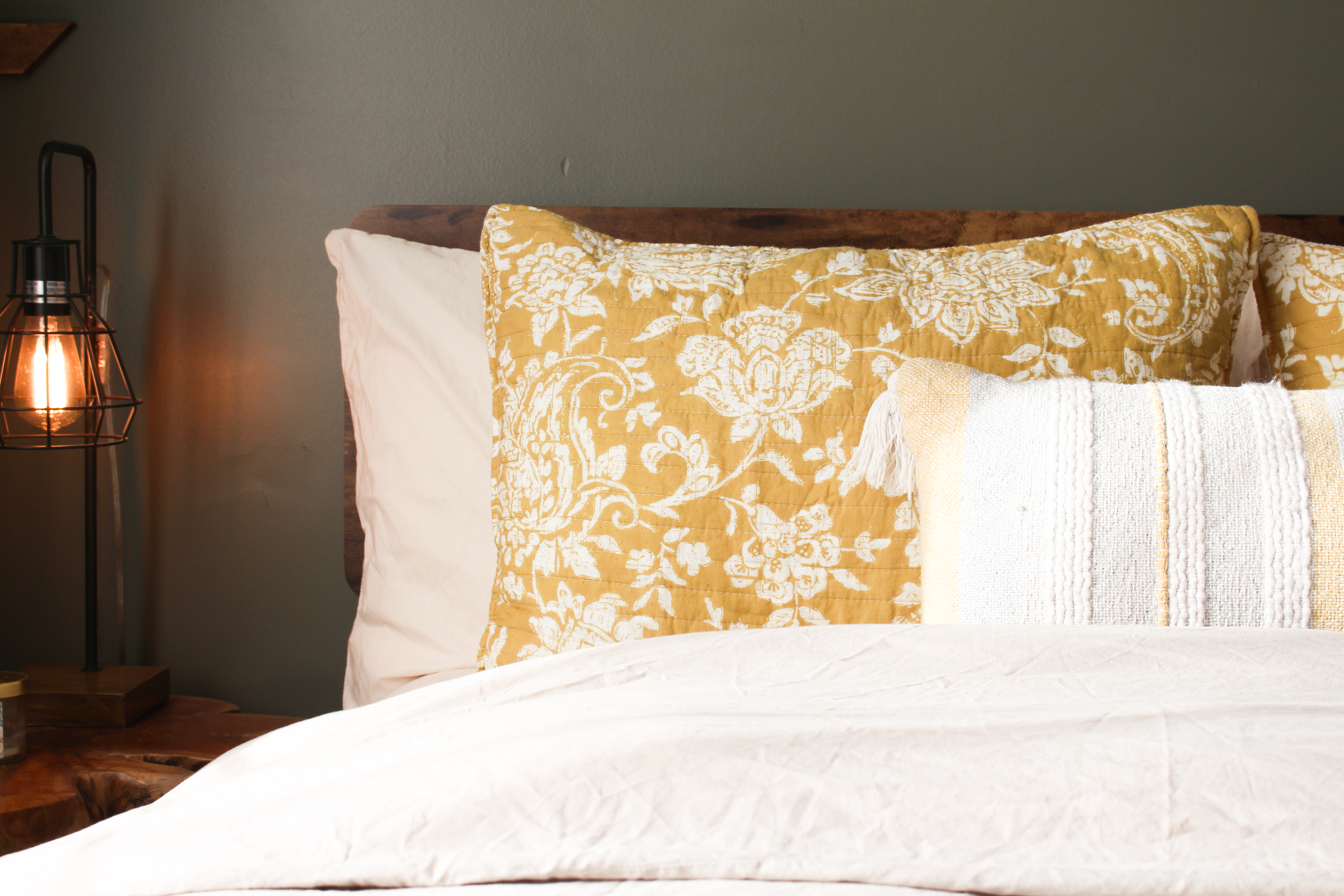 Bedroom detail: mustard floral pillow shams against a live-edge headboard
